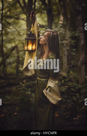 Schöne Frau im Märchenwald mit einer Laterne gehen. Dark fantasy Stockfoto