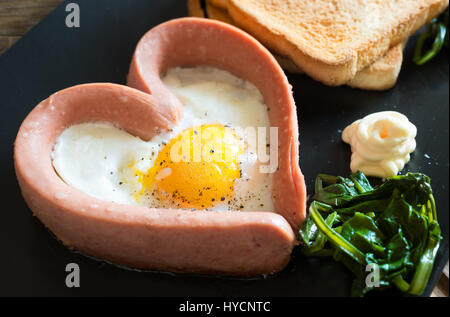 Spiegelei in der Pfanne in die Würstel Wurst Form des Herzens mit Mayonnaise und Gemüse Stockfoto