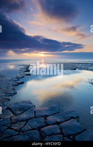 Sonnenuntergang spiegelt sich in einem Rockpool auf Dunraven Bay Stockfoto