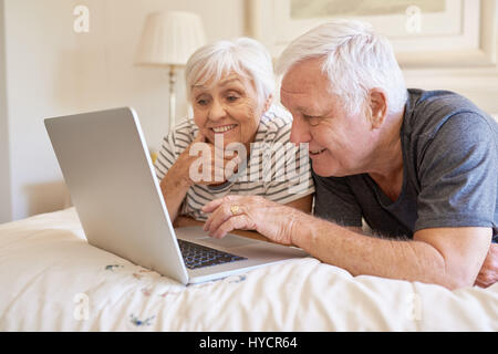 Gerne älteres Paar mit einem Laptop zusammen im Bett Stockfoto