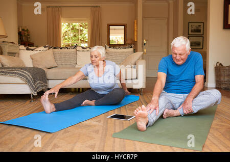 Aktive Senioren paar dehnen dabei Yoga zusammen zu Hause Stockfoto