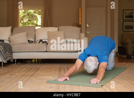 Aktiven senior Mann auf eine Yoga-Matte zu Hause trainieren Stockfoto