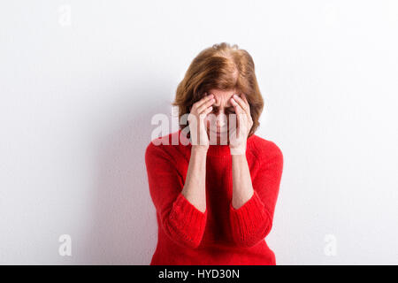 Ältere Frau Kopf haltend, mit Kopfschmerzen. Studio gedreht. Stockfoto