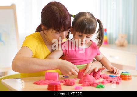 Süßes Kind und Mutter spielen mit Spielzeug zu Hause Bildhauerei. Kleine Mädchen Gebäude Sandburg. Stockfoto