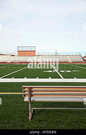 American Football Field mit Bank im Vordergrund und leere Tribüne Im Hintergrund Stockfoto
