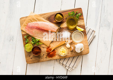 Rohe Tilapia und Zutaten auf Schneidebrett Stockfoto
