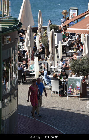 Hafen-Straße direkt neben dem Meer an einem windigen Tag mit geschlossenen Restaurant Schirme aber gefüllt mit Menschen, zwischen Weihnachten und Neujahr Gran Kanaren Stockfoto