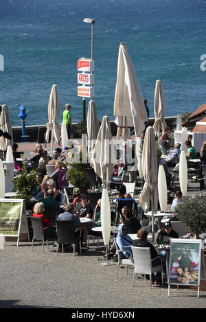 Hafen-Straße direkt neben dem Meer an einem windigen Tag mit geschlossenen Restaurant Schirme aber gefüllt mit Menschen, zwischen Weihnachten und Neujahr Gran Kanaren Stockfoto