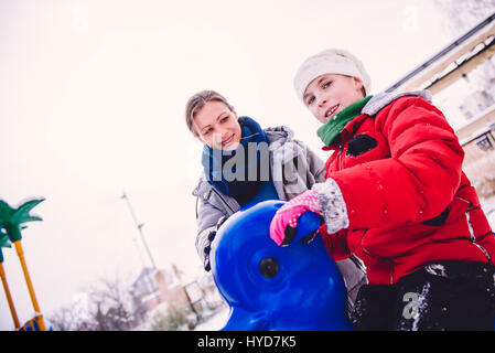 Mutter und Tochter auf Schnee überdachten Spielplatz Spaß haben Stockfoto