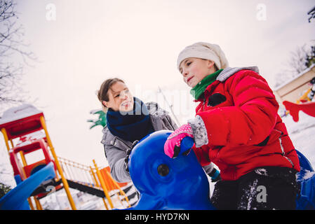 Mutter und Tochter auf Schnee überdachten Spielplatz Spaß haben Stockfoto