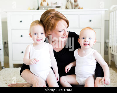 Portrait der Mutter, die Söhne (12-17 Monate) im Kinderzimmer hält Stockfoto