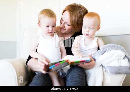 Mutter und Söhne (12-17 Monate) lesen Bilderbuch Stockfoto