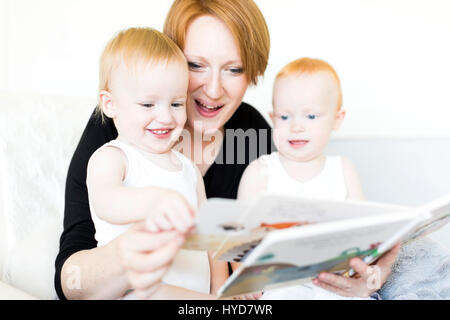 Mutter und Söhne (12-17 Monate) lesen Bilderbuch Stockfoto