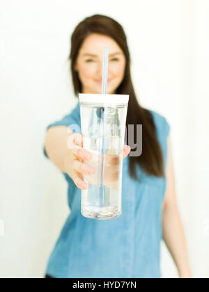 Frau trägt blaue Spitze hält Trinkglas Stockfoto