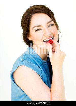 Frau trägt blaue Spitze Essen Himbeere Stockfoto