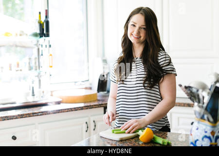 Frau schneiden Zitrone und Sellerie in der Küche Stockfoto