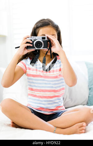 Sitzendes Mädchen (10-11) mit Kamera und Foto Stockfoto