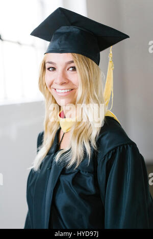 Porträt der jungen blonden Frau trägt Graduation Kleid Stockfoto