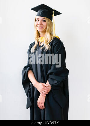 Porträt der jungen blonden Frau trägt Graduation Kleid Stockfoto