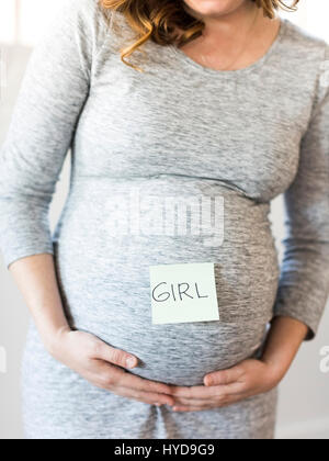 Porträt von lächelnden schwangeren Frau mit Klebstoff-Note auf dem Bauch Stockfoto