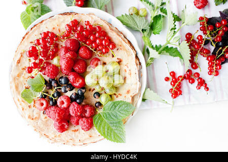 Stapel von dünnen goldenen Pfannkuchen mit frisch gepflückten Beeren und Minze auf einem Dessertteller Stockfoto