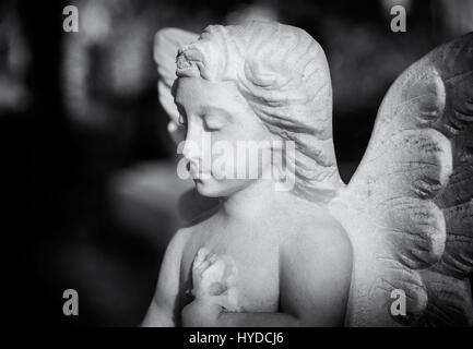 Betende Statue eines Winkels schaut auf ein Grab in einem Londoner Friedhof Stockfoto