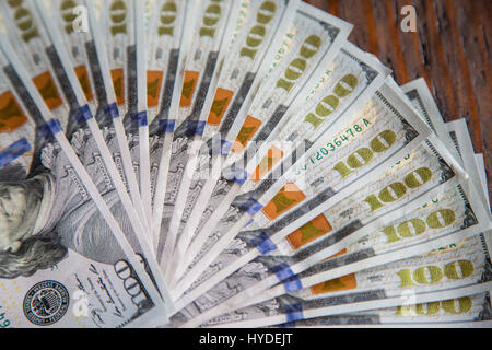 Ein Stapel von ganz neuen Hundert-Euro-Scheine in US-Währung schwärmten aus, auf einem dunkelbraunen hölzernen Tisch Stockfoto