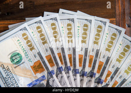 Ein Stapel von ganz neuen Hundert-Euro-Scheine in US-Währung schwärmten aus, auf einem dunkelbraunen hölzernen Tisch Stockfoto