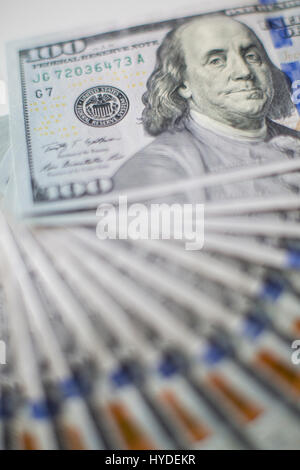 Ein Stapel von ganz neuen Hundert-Euro-Scheine in US-Währung schwärmten aus, auf einem dunkelbraunen hölzernen Tisch Stockfoto