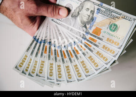 Ein Mann mit einer Hand zu Lüfter aus einem Stapel von ganz neuen Hundert-Euro-Scheine in US-Währung Stockfoto