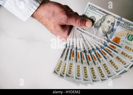 Ein Mann mit einer Hand zu Lüfter aus einem Stapel von ganz neuen Hundert-Euro-Scheine in US-Währung Stockfoto