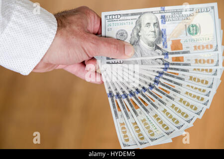 Ein Mann mit einer Hand zu Lüfter aus einem Stapel von ganz neuen Hundert-Euro-Scheine in US-Währung Stockfoto