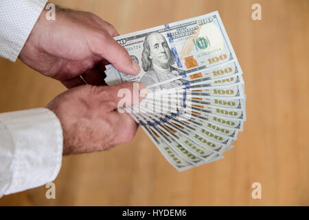 Ein Mann benutzt beide Hände zum Lüfter aus einem Stapel von ganz neuen Hundert-Euro-Scheine in US-Währung Stockfoto