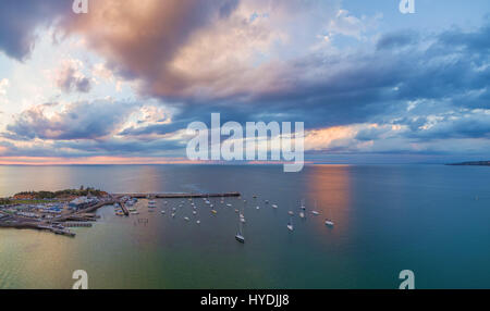 Aerial Panorama der Wolkengebilde über lange Pier und festgemachten Boote bei Sonnenuntergang Stockfoto