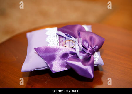 Hochzeiten-Ring auf dem Ruhe-Kissen auf braunem Hintergrund Stockfoto