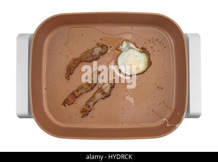 Draufsicht der drei Streifen Speck mit einem einzigen Ei Braten in einer großen Kupfer Keramik Pfanne isoliert auf einem weißen Hintergrund. Stockfoto