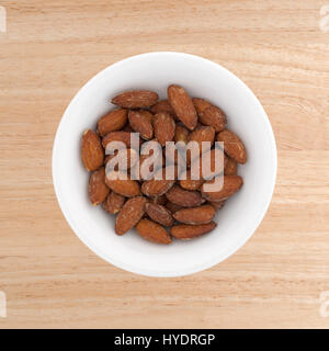 Draufsicht der Hickory geräucherte Mandeln in einer kleinen Schüssel auf einem Holztisch. Stockfoto