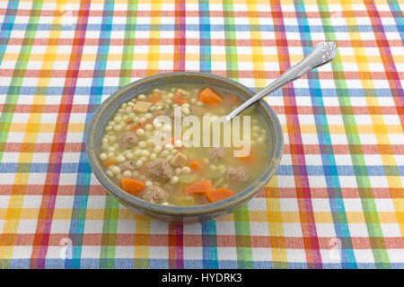 Schüssel mit italienischen Stil Hochzeit Suppe mit einem Löffel in das Essen auf einem bunten Tuch Tischset. Stockfoto