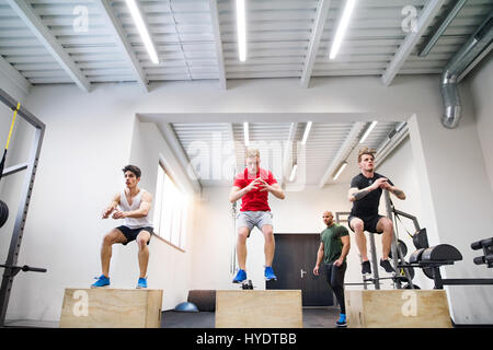 Männer im Fitnessraum mit Trainer trainieren auf Fit-Boxen. Stockfoto