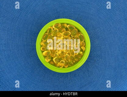Draufsicht auf eine Schüssel mit Vitamin-A-Gel-Kapseln auf einem blauen gewebte Tuch. Stockfoto