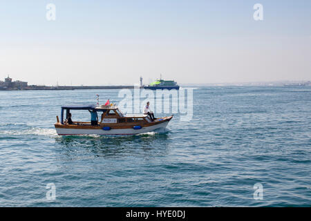 Kleines Fischerboot von Kadiköy in Istanbul verlassen. Moderne Fähre ist im Hintergrund. Stockfoto