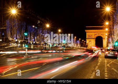 Autos streifen Sie die Champ-Elysees in Paris, Frankreich in der Weihnachtszeit mit dem Triumphbogen im Hintergrund. Stockfoto