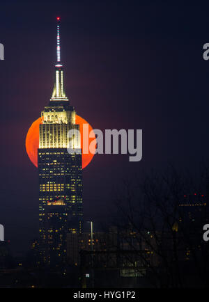 NEW YORK, USA: New Yorks legendären Empire State Building. GEFANGEN zwischen dem Mond und der New Yorker Freiheitsstatue scheint ihre Fackel mit einer orange Kugel des Lichts beleuchtet zu haben. Unglaubliche Bilder zeigen Full Blutmondes erhebt sich über die legendäre grüne Dame, beleuchten die Stadt unten in orange Farbtöne.  Andere Bilder zeigen das Empire State building wird wieder durch diese spektakuläre himmlische Scheibe beleuchtet. Amerikanische Technische Redakteurin Jennifer Khordi (46) war in der Lage, diese beeindruckenden Aufnahmen von der Skyline von Jersey City und Kearny Stadt in New Jersey zu erfassen. Stockfoto