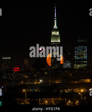 NEW YORK, USA: New Yorks legendären Empire State Building. GEFANGEN zwischen dem Mond und der New Yorker Freiheitsstatue scheint ihre Fackel mit einer orange Kugel des Lichts beleuchtet zu haben. Unglaubliche Bilder zeigen Full Blutmondes erhebt sich über die legendäre grüne Dame, beleuchten die Stadt unten in orange Farbtöne.  Andere Bilder zeigen das Empire State building wird wieder durch diese spektakuläre himmlische Scheibe beleuchtet. Amerikanische Technische Redakteurin Jennifer Khordi (46) war in der Lage, diese beeindruckenden Aufnahmen von der Skyline von Jersey City und Kearny Stadt in New Jersey zu erfassen. Stockfoto