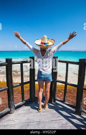 Hintere Ansicht Porträt von Ypoung Frau, die am Strand mit ihr die Hände weit offen in Tulum, Mexiko Stockfoto