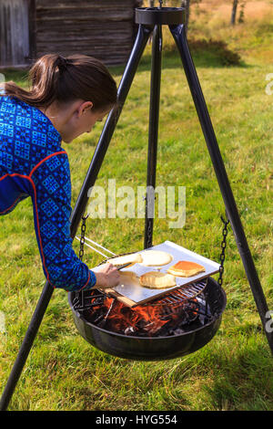 Frau Pfannkuchen am Lagerfeuer zubereiten Stockfoto