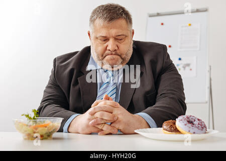 Unsicheren übergewichtigen Mann mit Blick auf eine harte Wahl Stockfoto