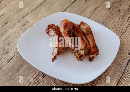 Schweinefleisch Rippen gegrillt auf Nahaufnahme BBQ Ribs mit Wedges auf einem weißen Teller. Stockfoto
