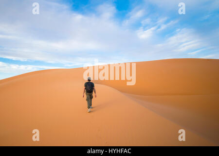 Ein Mann geht auf den Dünen in der Wüste Sahara bei Sonnenuntergang - Merzouga - Marokko Stockfoto