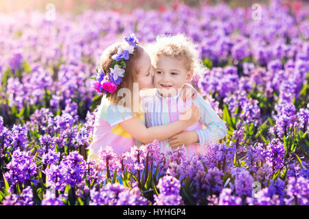 Kinder im Garten. Kinder spielen im Freien auf Hyazinthen Wiese. Kleine Mädchen und jungen, Bruder und Schwester, arbeiten im Garten, Hyazinthe Blumen Pflanzen, wa Stockfoto